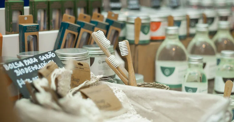 Produtos ecológicos expostos numa loja, com escovas de dentes de bambu, frascos reutilizáveis e embalagens sustentáveis