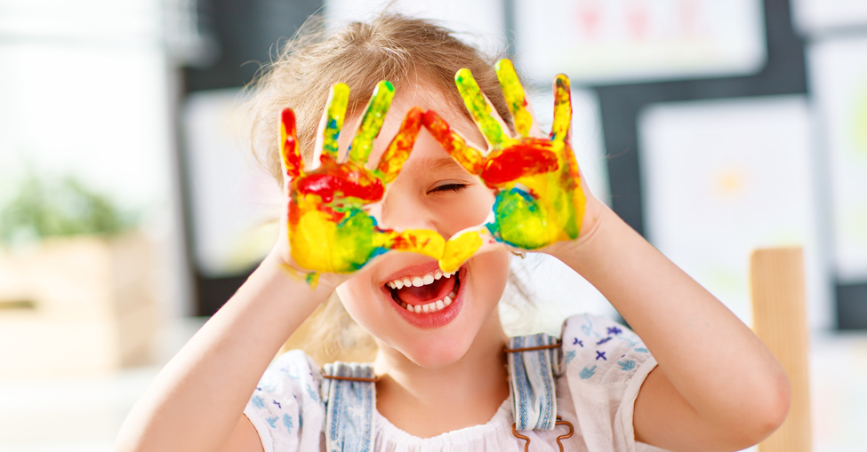 Criança com as mãos pintadas.